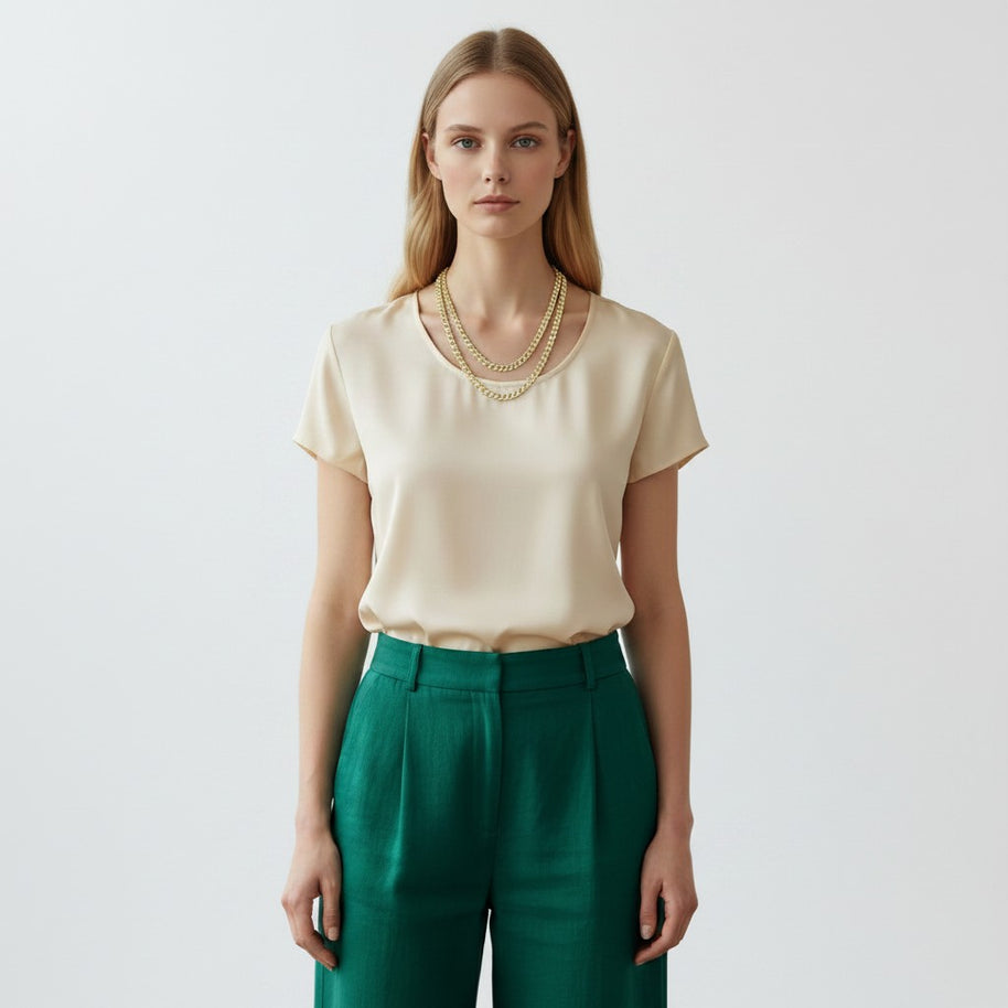 Model wearing a TYS Jewelers 10K yellow gold two-tone diamond cut Cuban chain necklace with a cream top