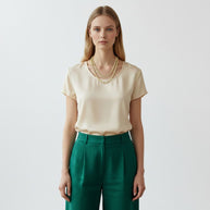 Model wearing a TYS Jewelers 10K yellow gold two-tone diamond cut Cuban chain necklace with a cream top