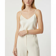 TYS Jewelers 10K yellow gold Miami Cuban link bracelet worn on a model's wrist with a cream silk camisole.