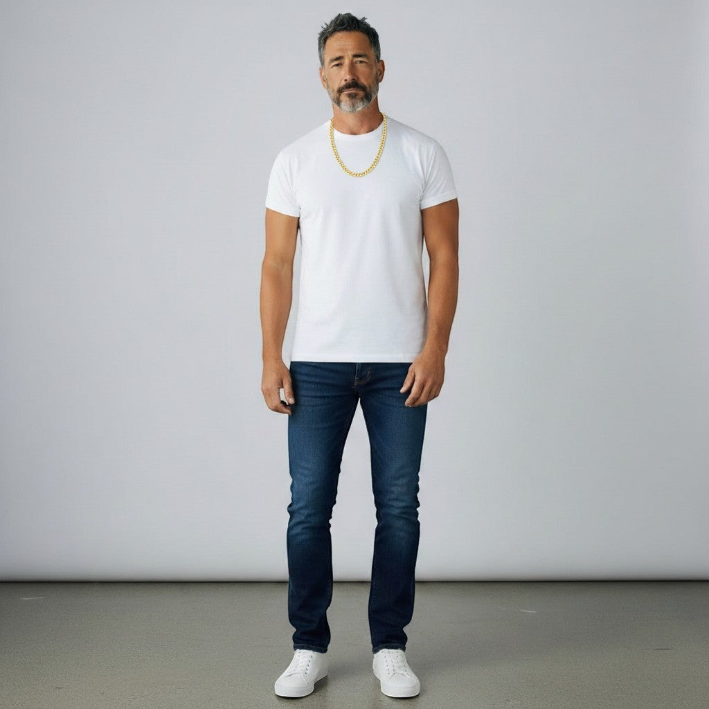 TYS Jewelers 10K yellow gold curb Cuban chain worn by a man in a white t-shirt and blue jeans against a grey backdrop.