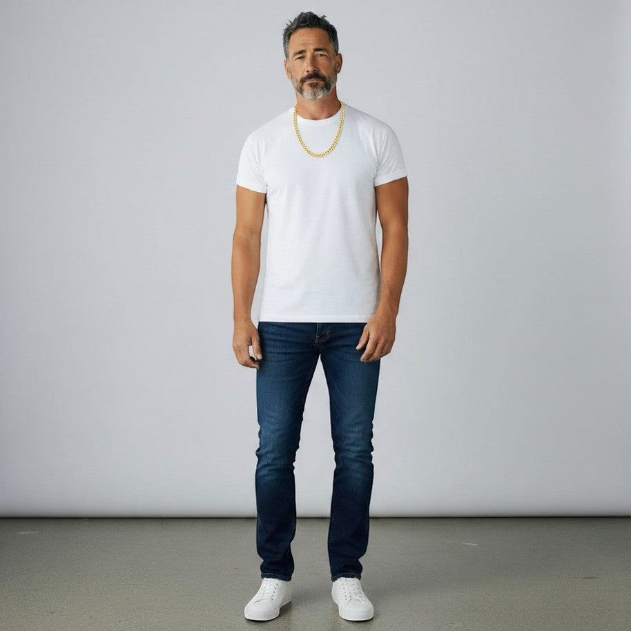 TYS Jewelers 10K yellow gold curb Cuban chain worn by a man in a white t-shirt and blue jeans against a grey backdrop.