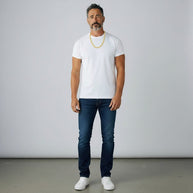 TYS Jewelers 10K yellow gold curb Cuban chain worn by a man in a white t-shirt and blue jeans against a grey backdrop.