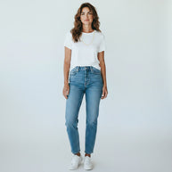 A woman wearing a TYS Jewelers 10K yellow gold Figaro chain with a white t-shirt and blue jeans