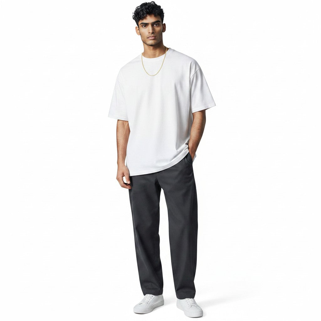 A man wearing a TYS Jewelers 10K yellow gold Figaro chain with a white t-shirt and dark trousers
