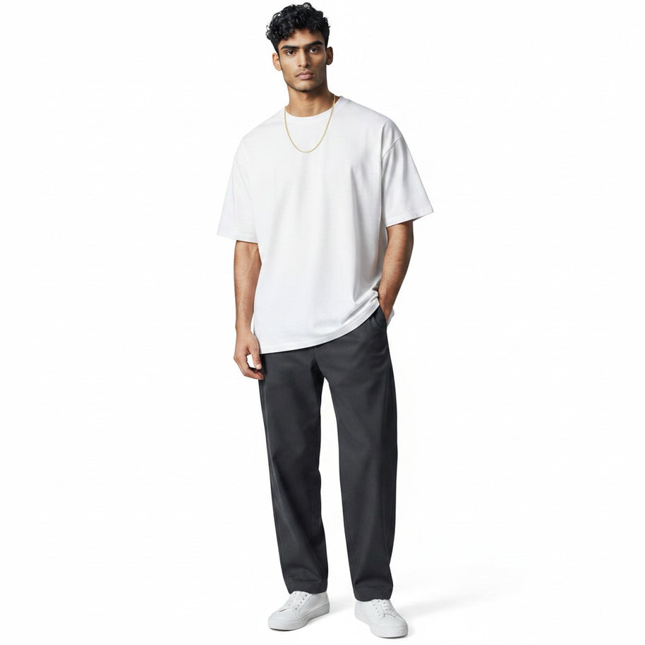 A man wearing a TYS Jewelers 10K yellow gold Figaro chain with a white t-shirt and dark trousers