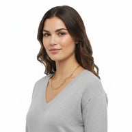 TYS Jewelers 10K yellow gold two-tone diamond-cut figaro chain worn by a woman in a grey V-neck sweater